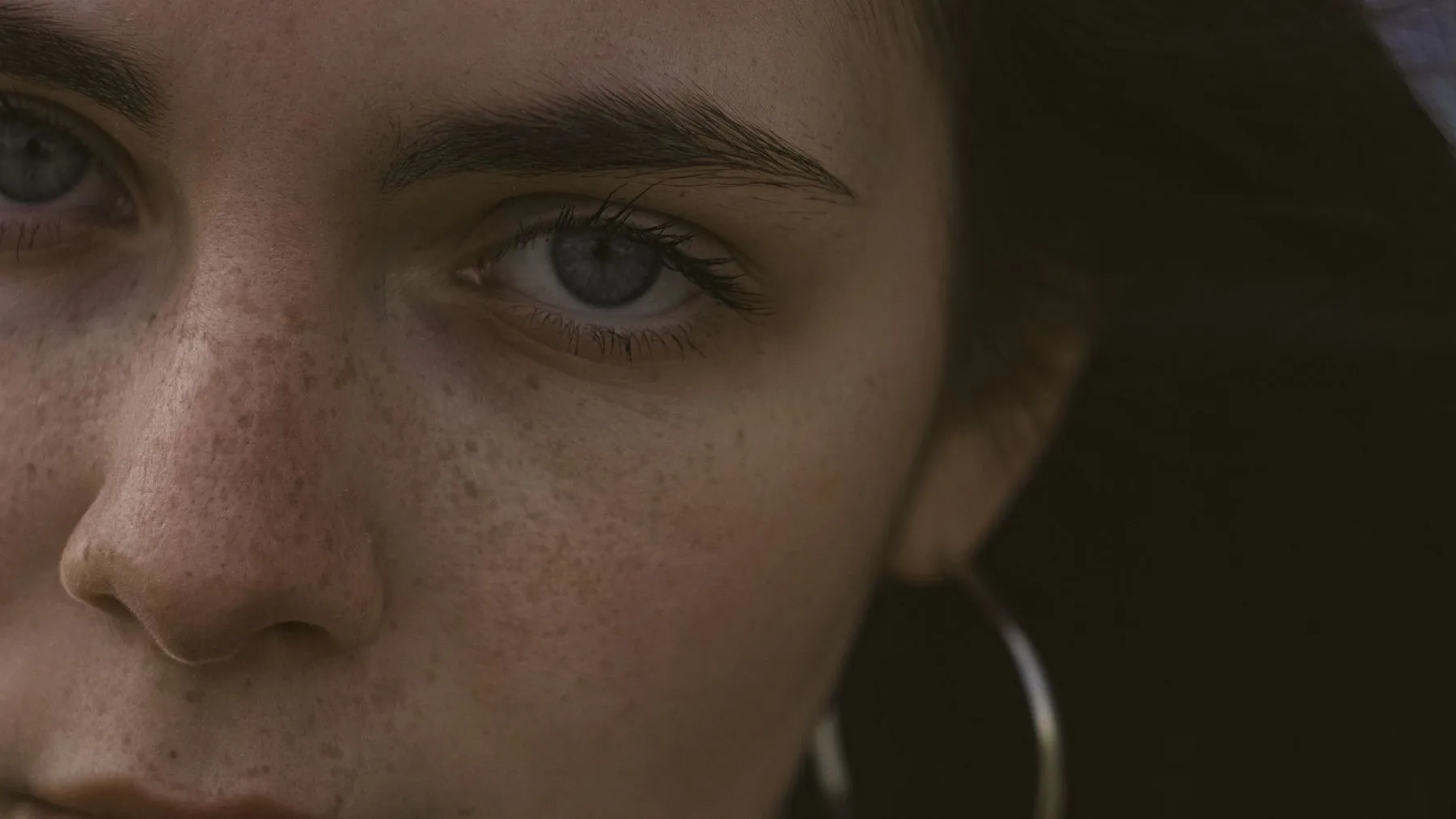 Half of a woman's face in low light, brow and eye